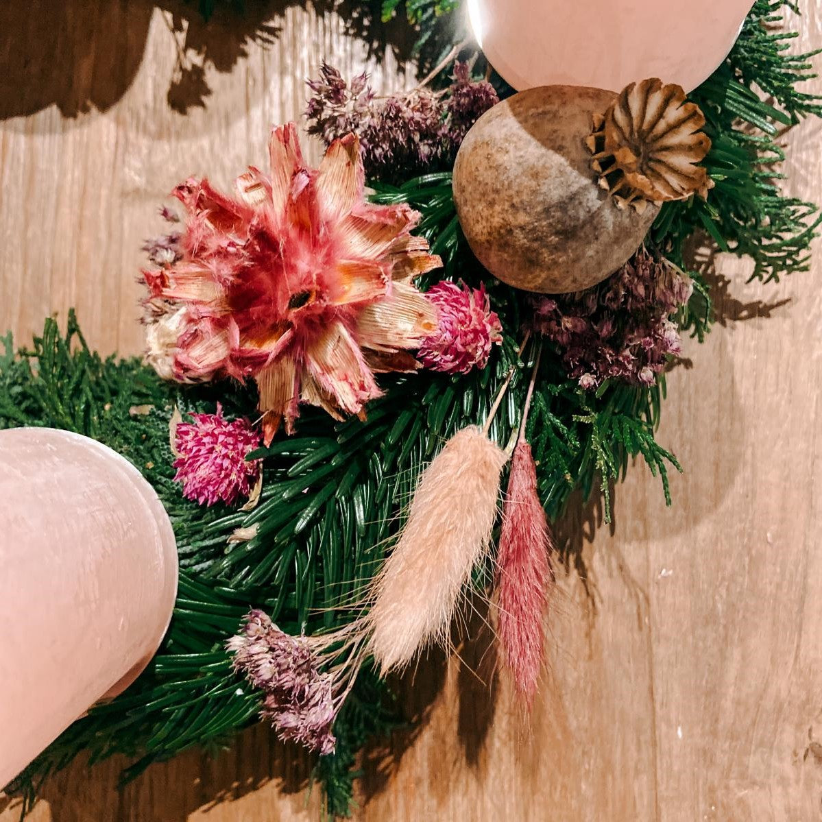 Verschiedene rosa Blüten und Naturmaterialien auf Kranz – Adventskranz Rosenrot gestalten.