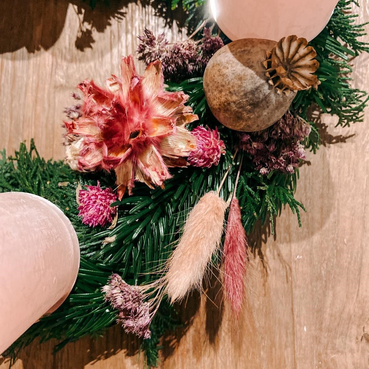 Verschiedene rosa Blüten und Naturmaterialien auf Kranz – Adventskranz Rosenrot gestalten.