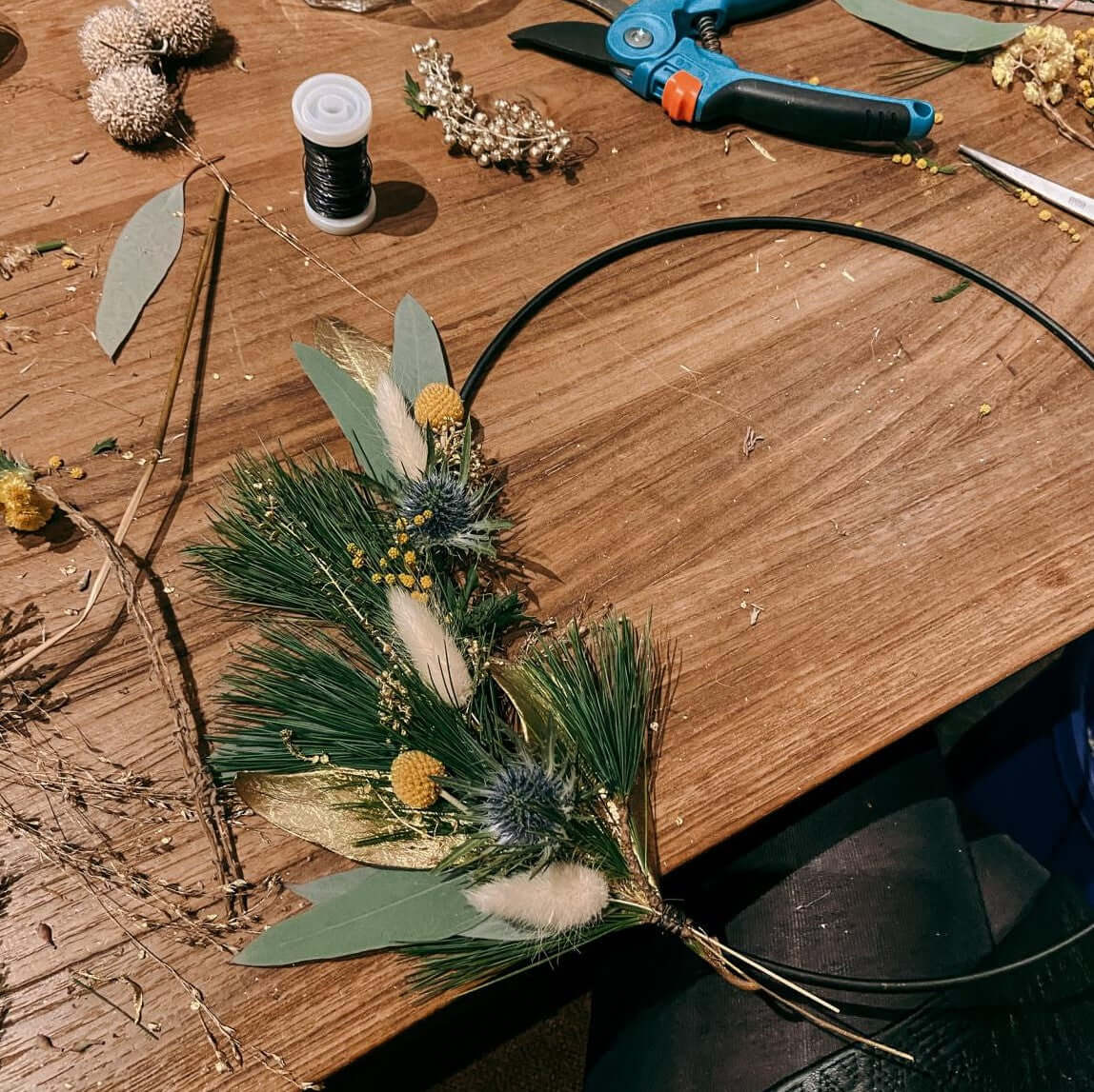 Angefangener Deko-Ring mit Materialien auf Tisch – eukalyptus ring, weihnachtsdeko workshop berlin.
