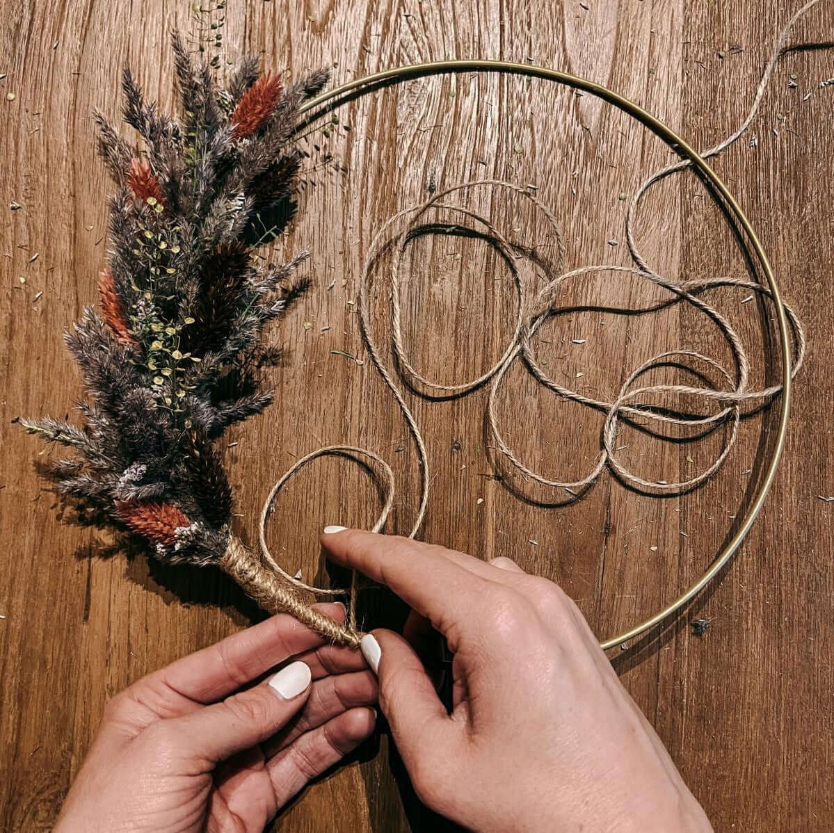 Hand wickelt Cord-Garn um Metallring – Vorbereitung für DIY Trockenblumenring Lachsflieder.