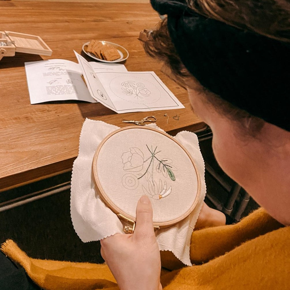 Frau bearbeitet Stickerei auf Stoff mit Garn – Blumenmotiv Workshop DIY.