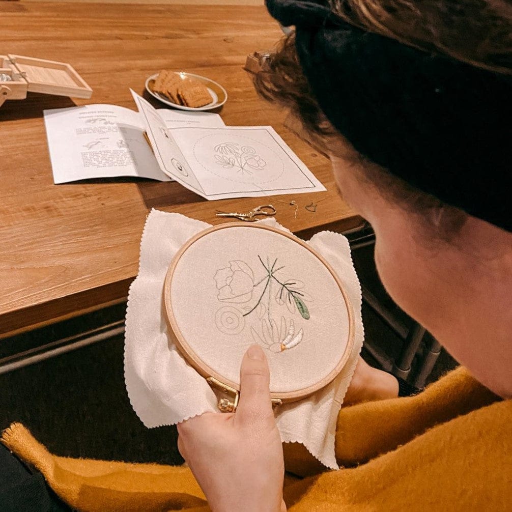 Frau bearbeitet Stickerei auf Stoff mit Garn – Blumenmotiv Workshop DIY.