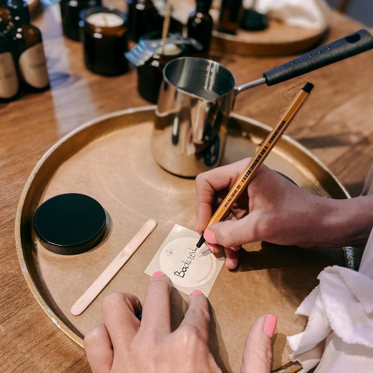 Hand schreibt auf Zettel neben geschmolzenem Wachs – vegane Kerzen Workshop, Firmenevent möglich.