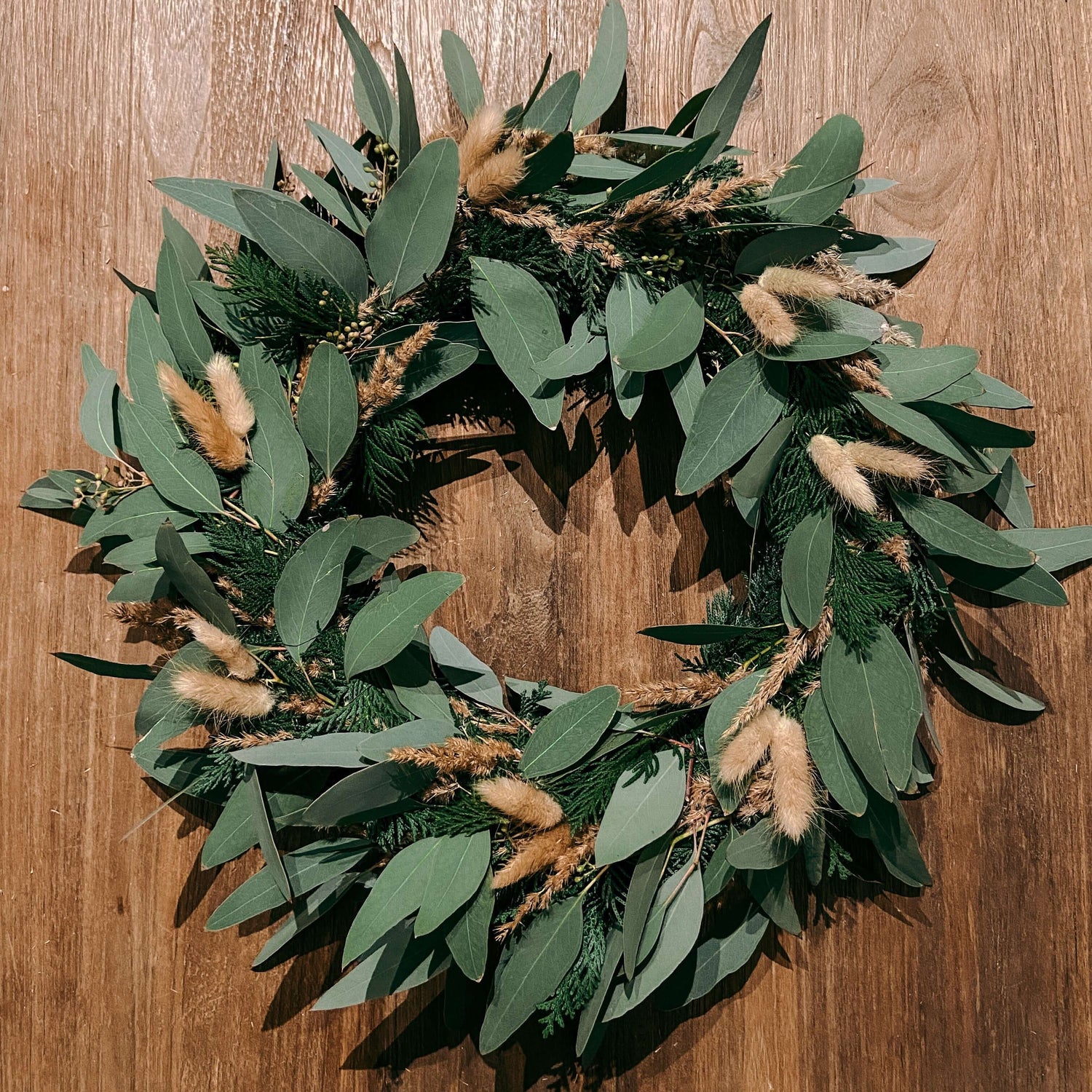 Fertiger Kranz aus Eukalyptus, Tannenzweigen und braunen Trockenblumen – eukalyptus kranz, weihnachtsdeko, auch für Firmenevents.