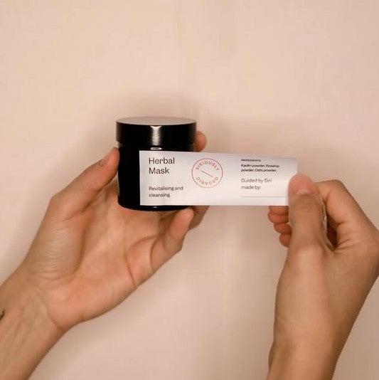 Hand klebt Sticker auf Maskentube – personalisierte, vegane Kräutermaske aus DIY Kosmetikbox.