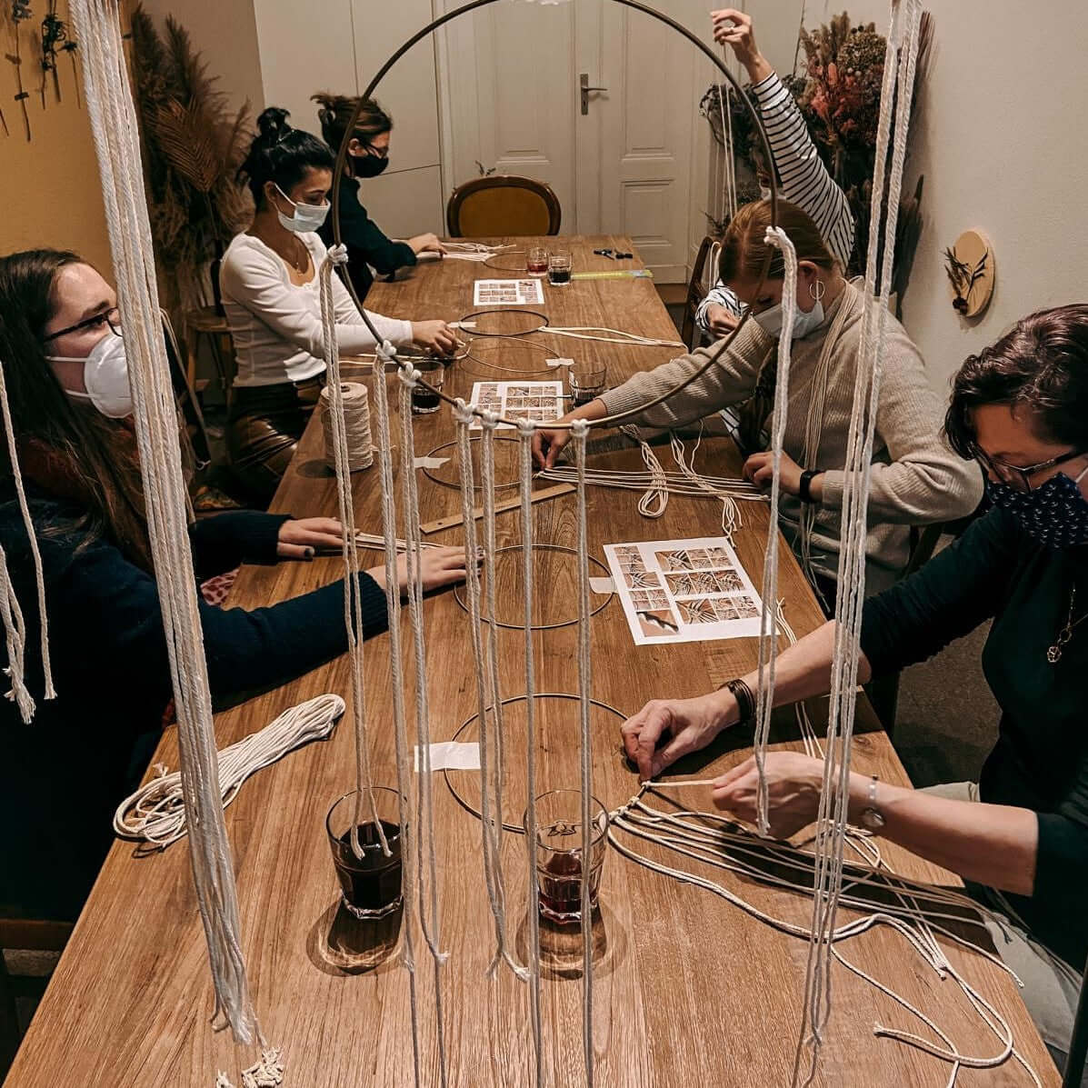 Makramee-Kurs mit Arbeitsplätzen und Materialien auf dem Tisch – Workshop Atmosphäre, Handarbeit, Berlin.
