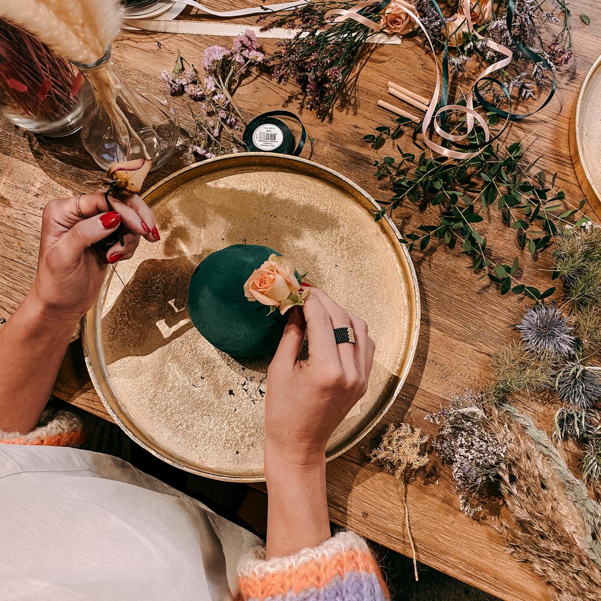 Zwei Hände bearbeiten FlowerBall mit goldenem Tablett im Hintergrund – Workshop für Teams oder Einzelpersonen.