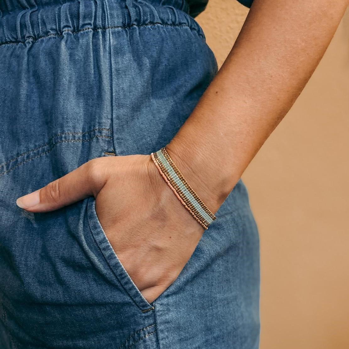 Hand mit Ring und Armband auf Holztisch – Miyuki Armband Workshop, handgemachter Schmuck