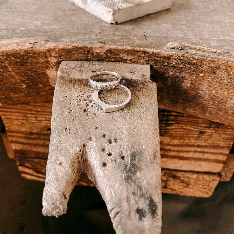 Zwei Silberringe auf Holzplattform präsentiert – DIY Ring Workshop, Ring selbst designen, Handarbeit.