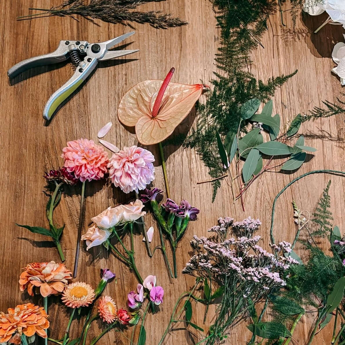 Verschiedene Blumen liegen auf Holztisch – Blumenkrone Workshop mit frischen Schnittblumen.