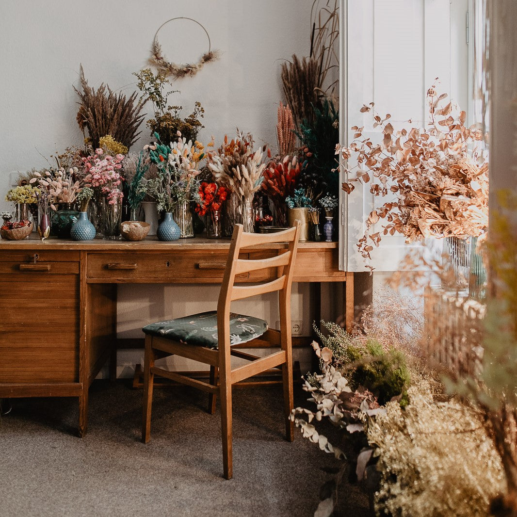 Tisch mit bunten Trockenblumen – Materialien für Glasglocken Workshop im Boho Stil.