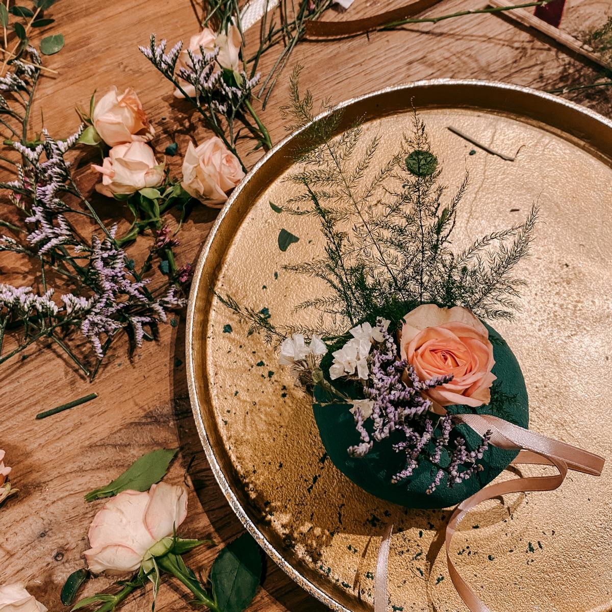 Goldenes Tablett mit angefangenen FlowerBalls in Rosa und Lila und Blumen auf Tisch – kreativer Workshop.