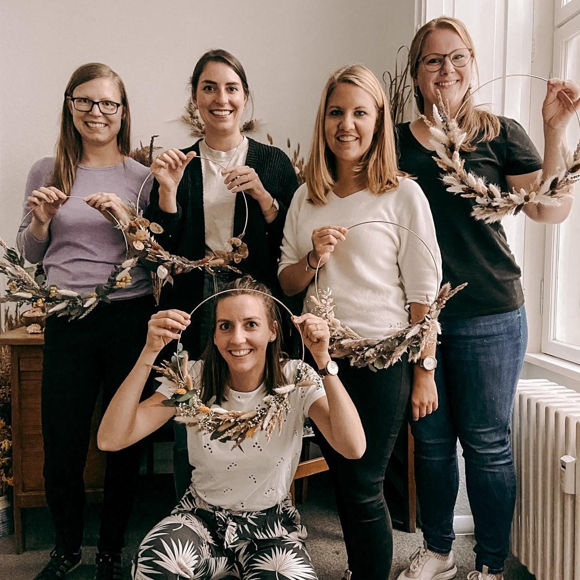 Fünf Teilnehmerinnen halten lächelnd ihre Trockenblumenringe – DIY Workshop, Boho, Firmenevent, JGA.