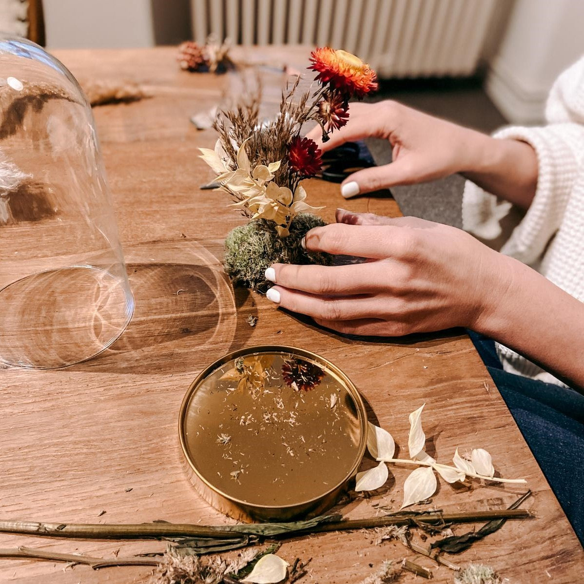 Hände gestalten Glasglocke mit bunten Blumen – kreative Trockenblumen Glasglocke DIY.