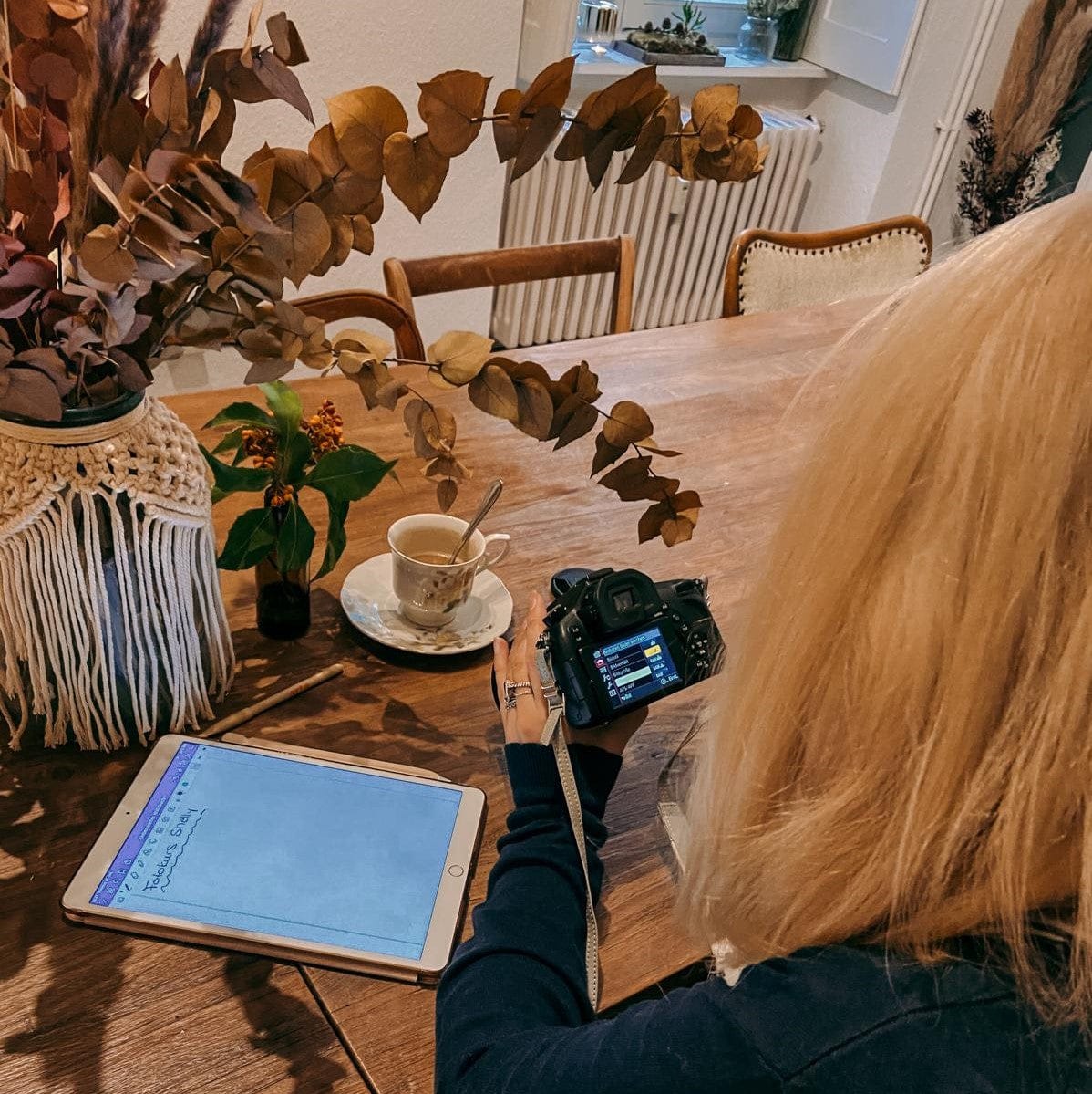 Person schaut Kamera an, Tee auf Tisch – Fotokurs Wild Lights, Kamera kennenlernen und manuell fotografieren.