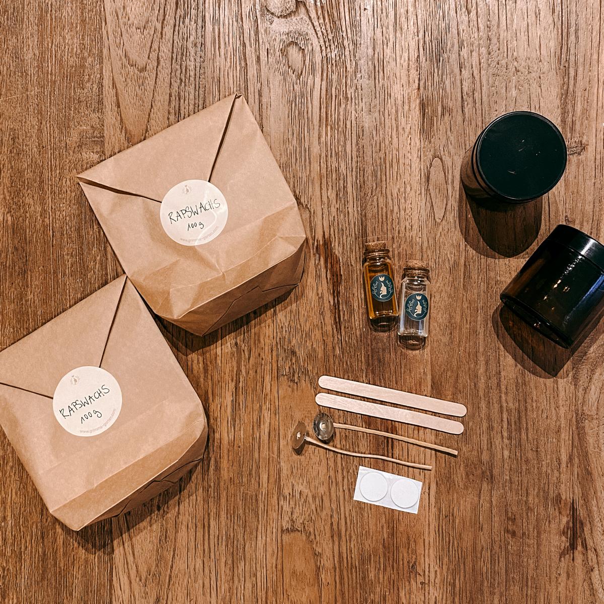Materialien der DIY Box Vegane Duftkerze: Rapswachs, Holzspatel, Dochte und Öle auf Tisch.