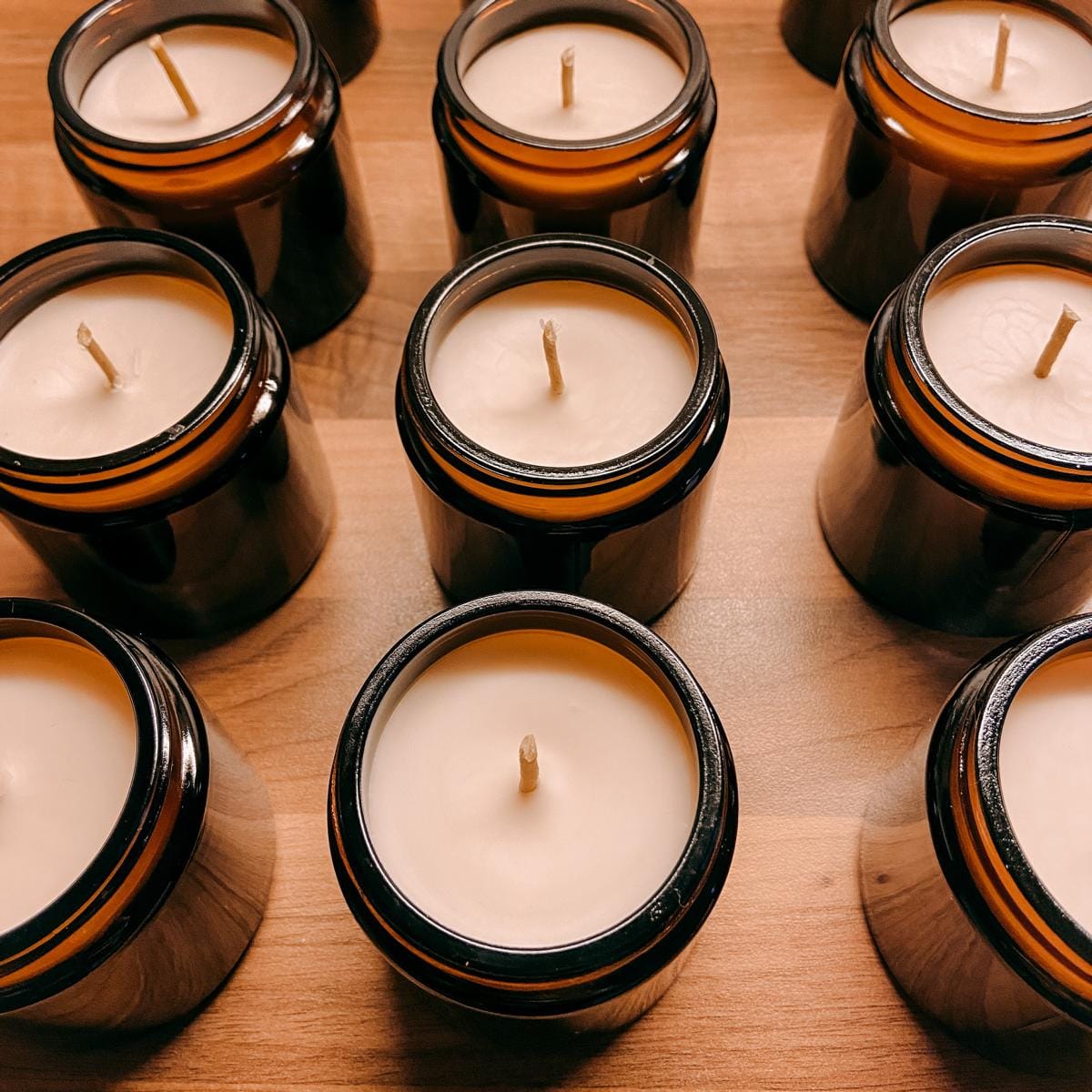 Viele fertige vegane Duftkerzen auf Holztisch – DIY Kerzen Workshop, auch für Firmenevents.