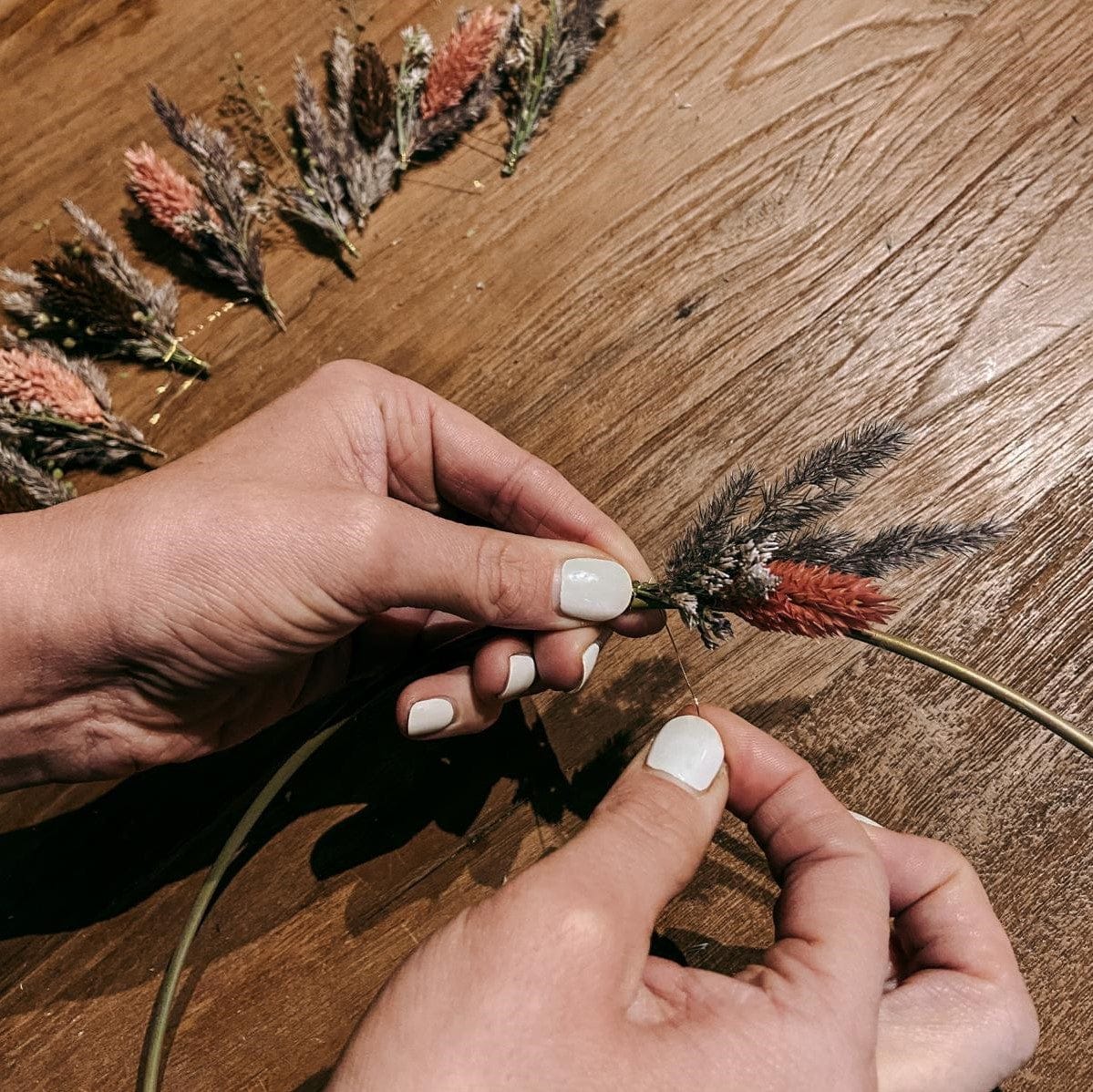 Hand befestigt Trockenblumen mit Draht am Ring – kreative Bastelarbeit mit der DIY Box.