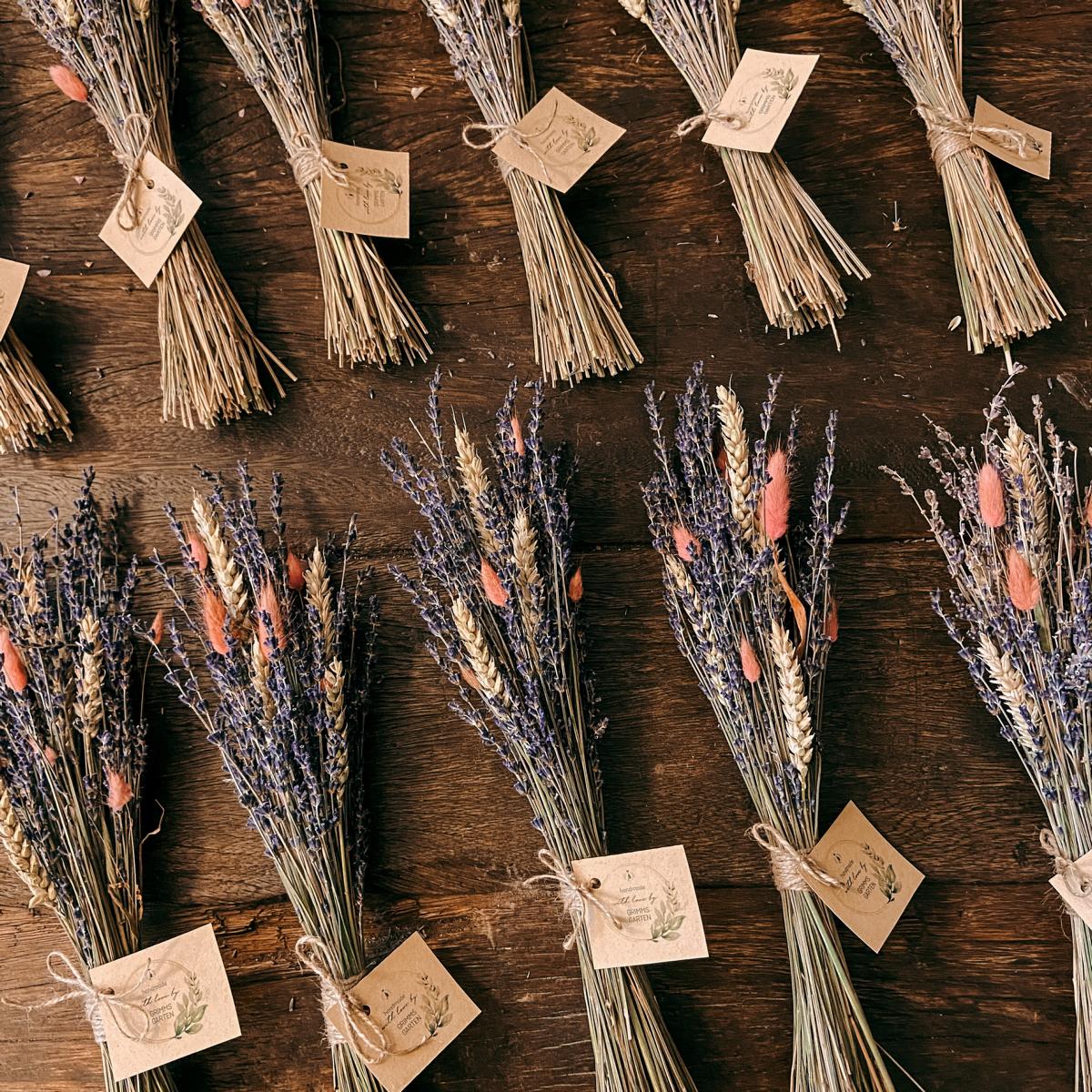 Mehrere Lavendel-Trockensträuße mit Gerste und Lagurus auf Tisch, stilvolle Deko für Tisch oder Raumgestaltung.