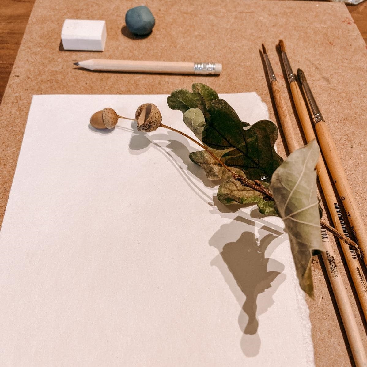 Blatt mit Pinsel, Zweigen und Bleistift auf Tisch – kreative Aquarellgestaltung Herbst.