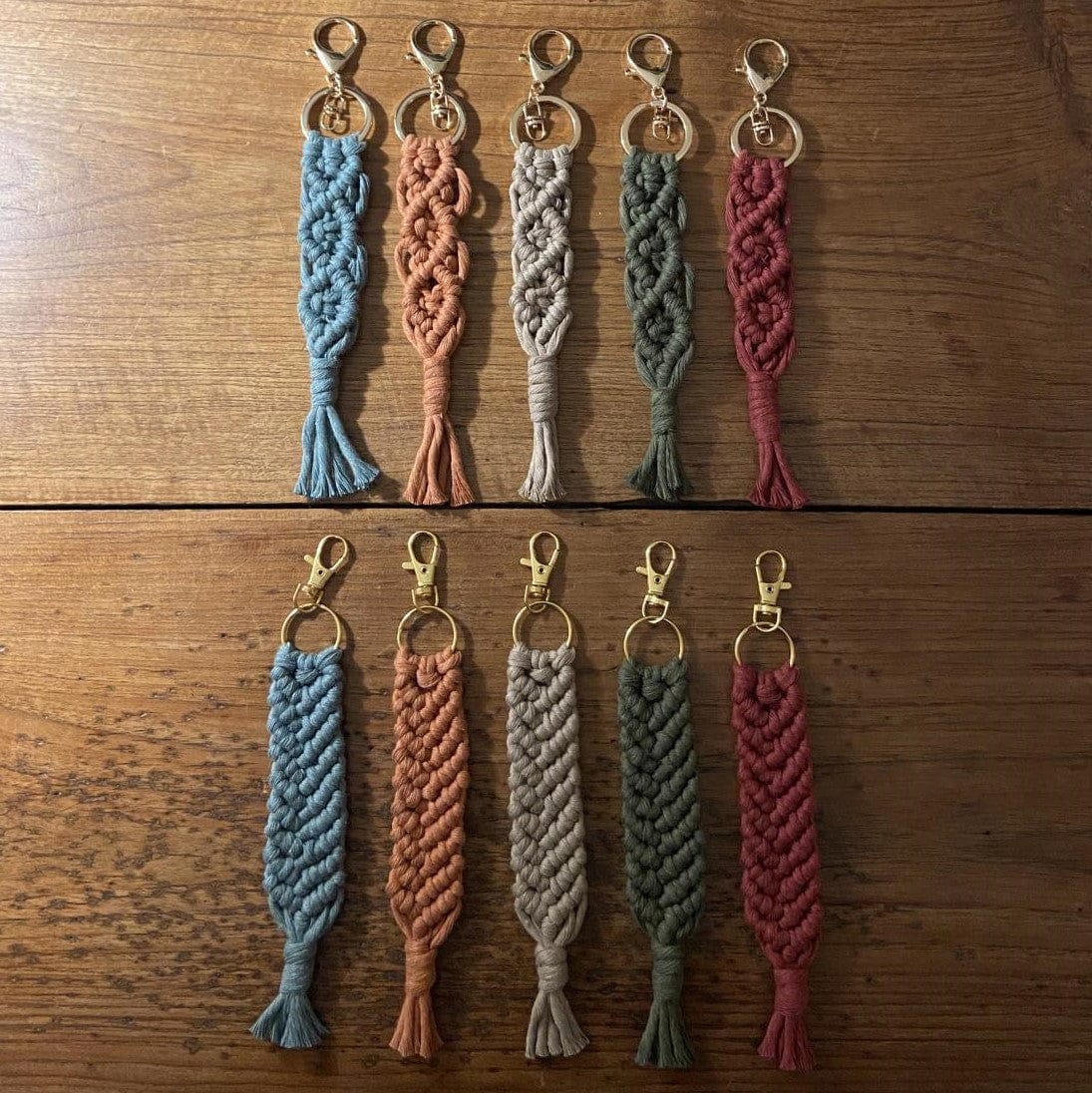 Viele Makramee Schlüsselanhänger in verschiedenen Farben und Formen auf Tisch ausgebreitet.