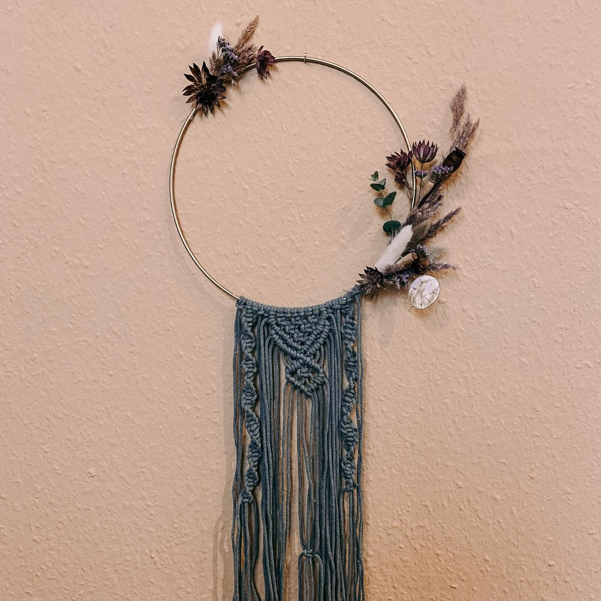Blumen Makramee Ring in Blau mit lila Blumen an Wand – kreative Boho Dekoration.