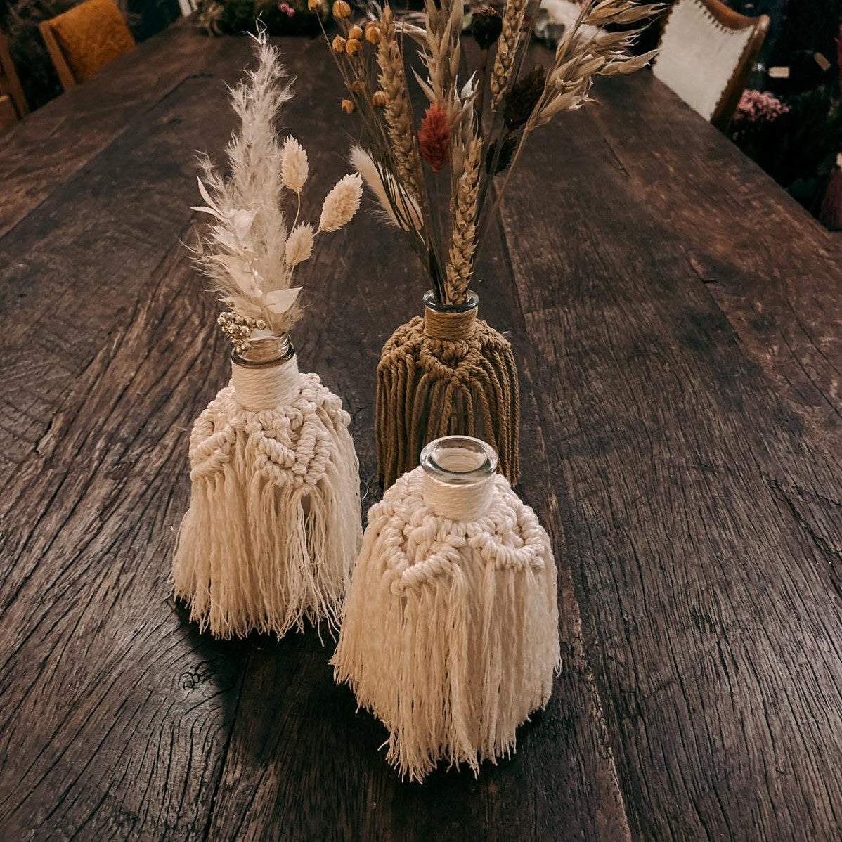 Zwei helle und eine braune Makramee Vase nebeneinander, dekorative Boho-Accessoires.