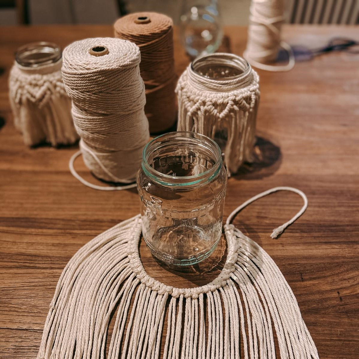 Glas mit Makramee und Garn im Hintergrund – kreative Boho Lichtgläser im Makramee Workshop.