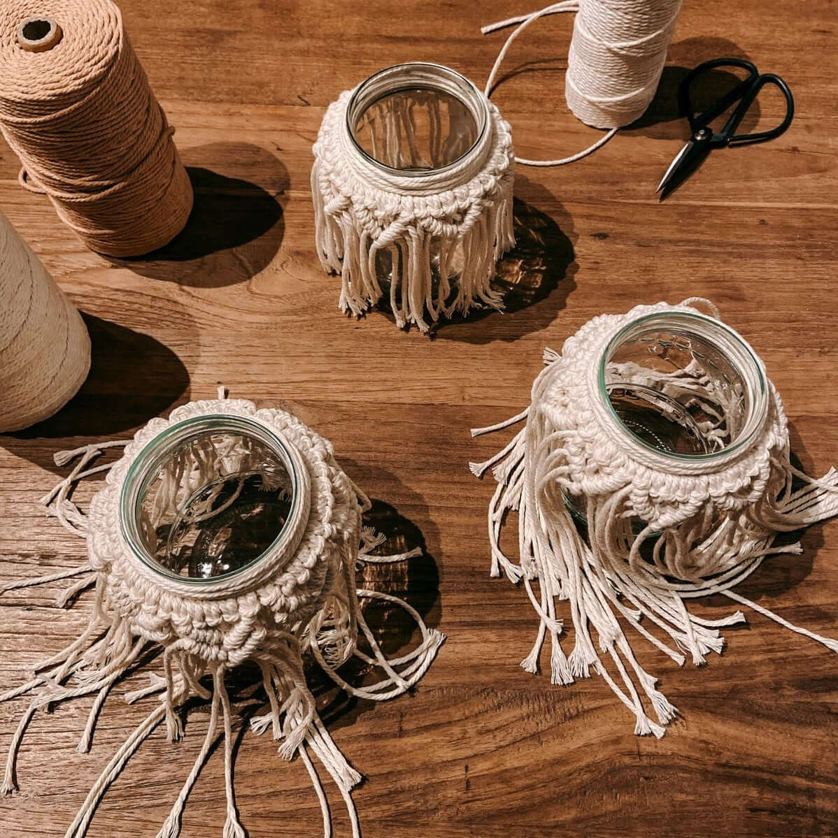 Drei fertige Makramee Gläser von oben fotografiert – kreative Boho Lichtgläser selbstgemacht.