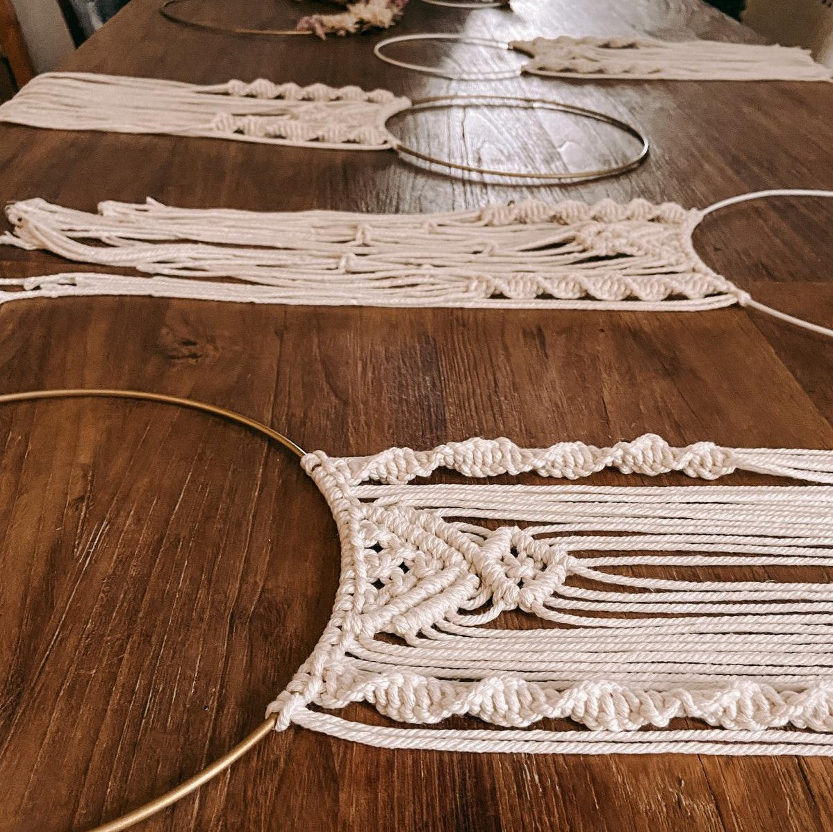 Viele fertige Makramee Ringe auf Tisch ausgebreitet, bunte Wanddeko Ideen.