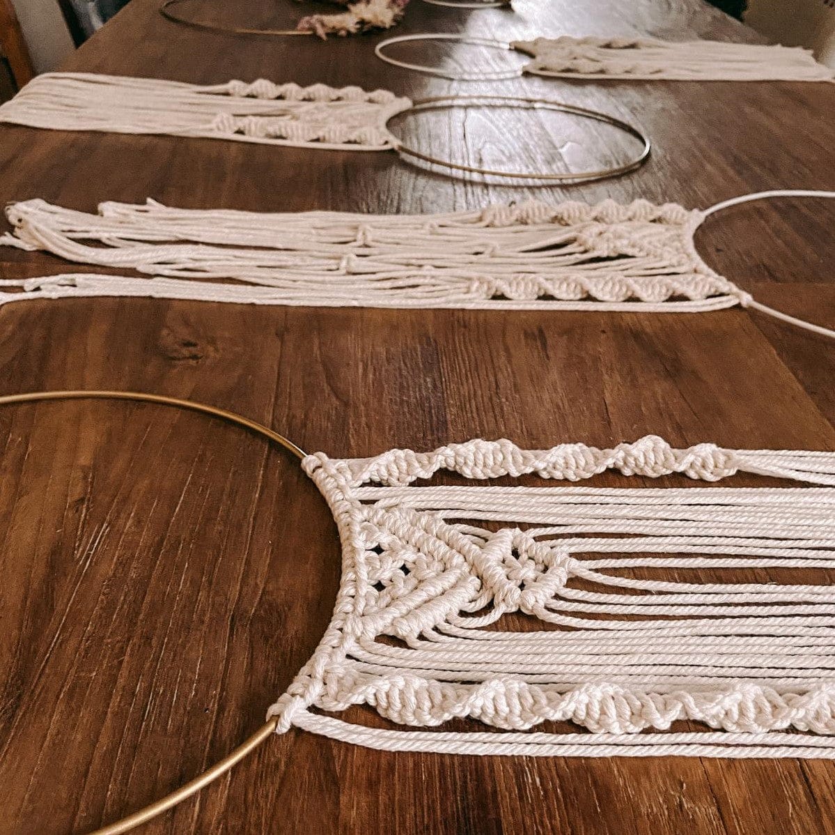 Viele fertige Makramee Ringe auf Tisch ausgebreitet, bunte Wanddeko Ideen.