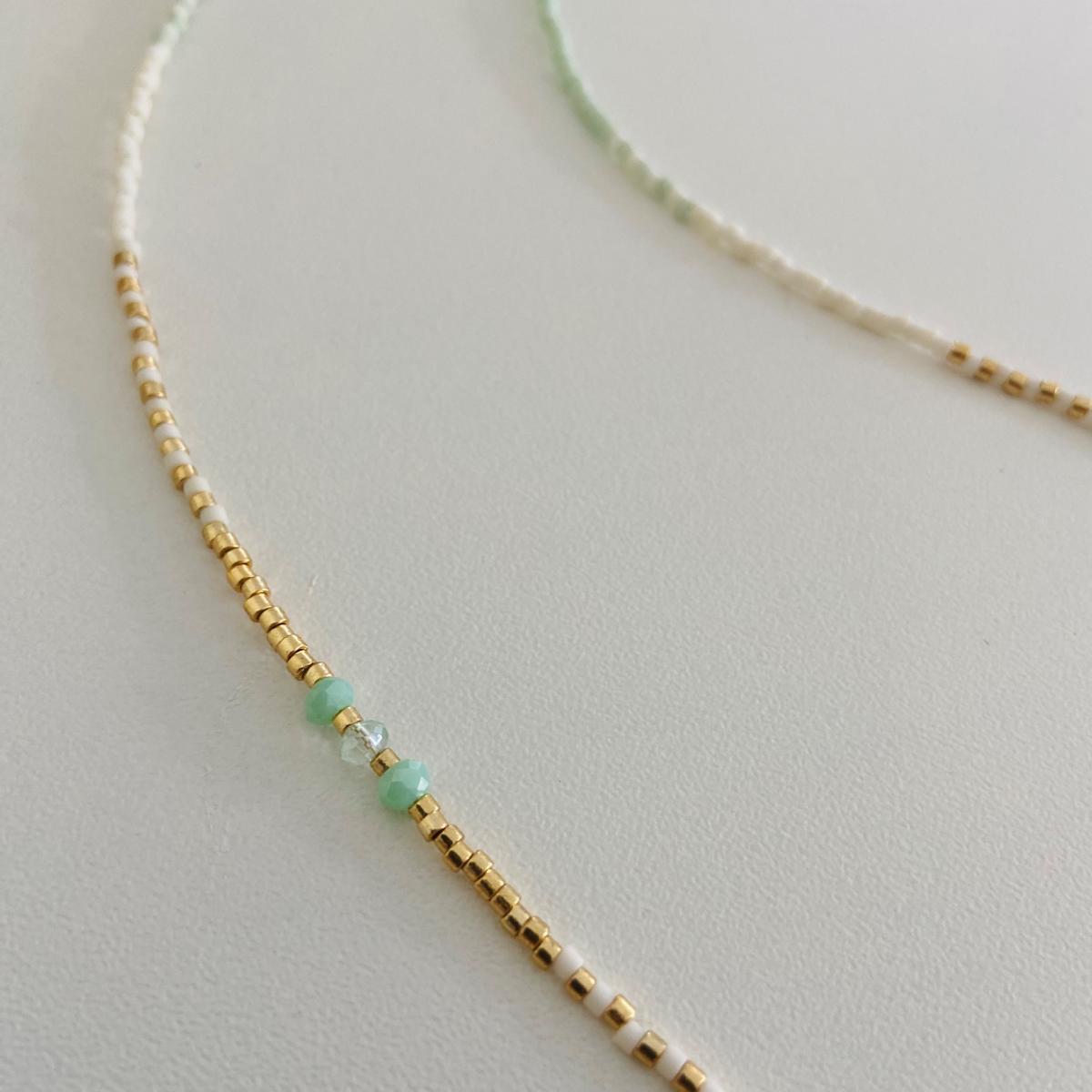 Nahaufnahme der Perlenkette „Summerfeeling“ in Mint, Weiß und Gold auf Tisch präsentiert.