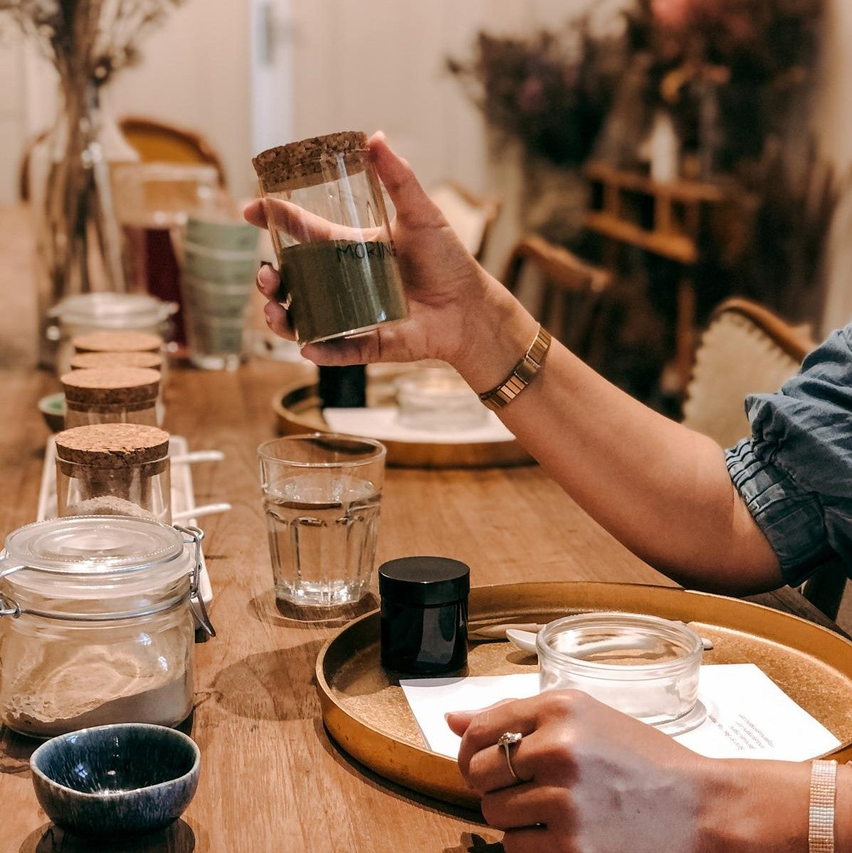 Hand hält Einmachglas mit grünem Pulver – vegane Gesichtsmasken selber machen.