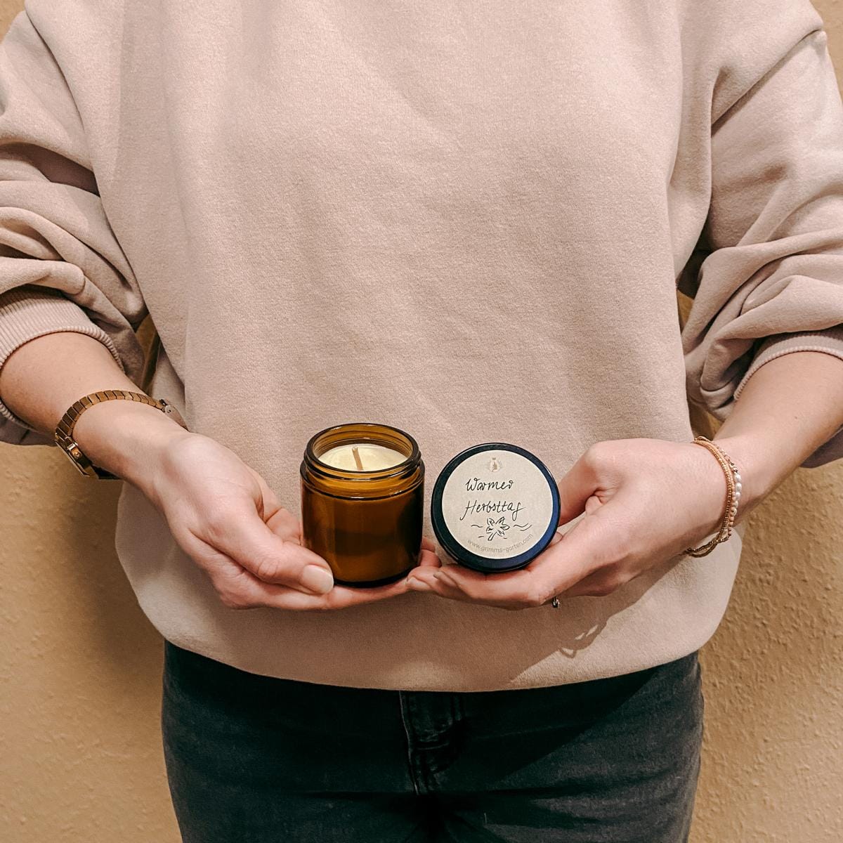 Person hält Kerze mit Deckelaufschrift „Warmer Herbsttag“ – natürliche Duftkerze DIY.