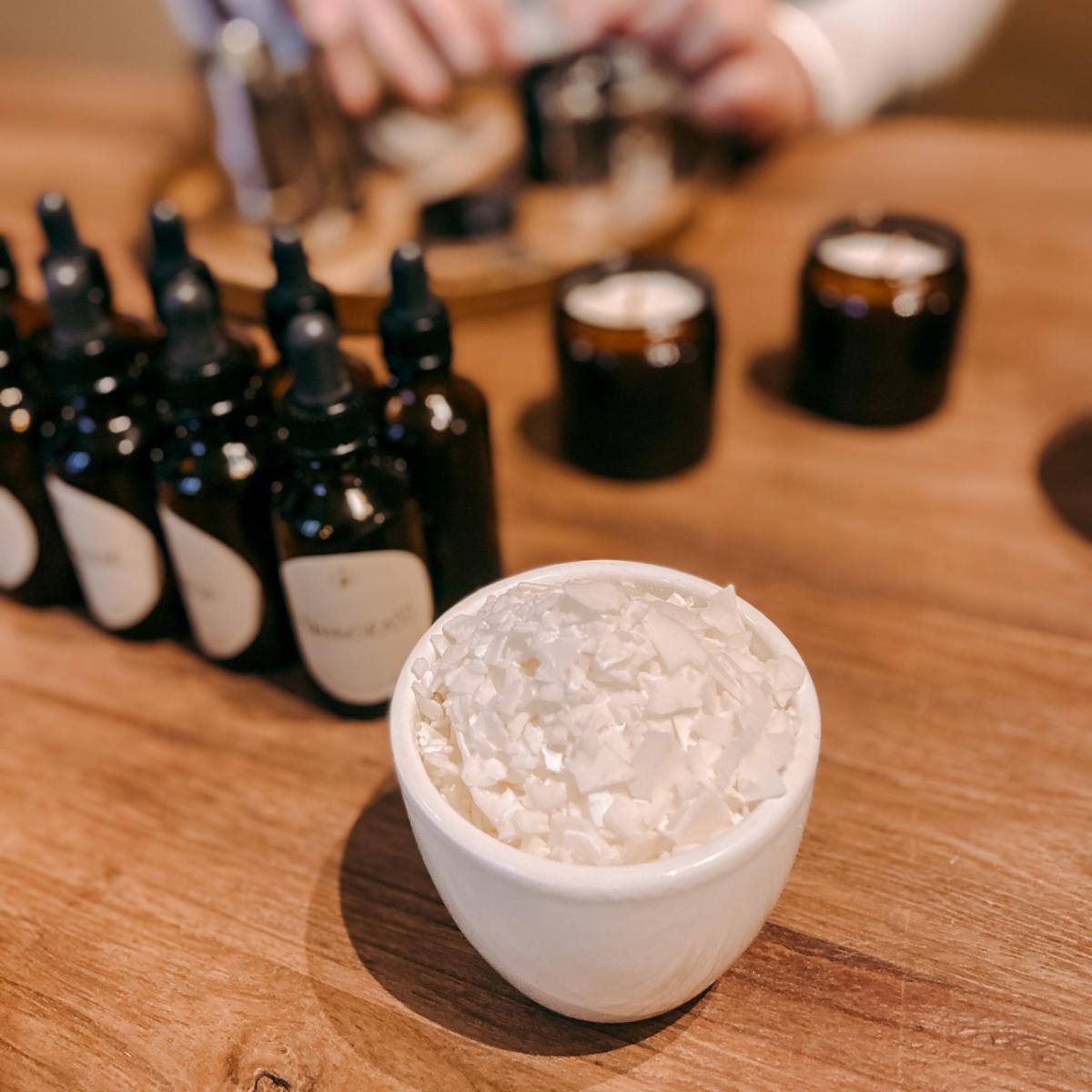 Behälter mit Kerzenwachschips, viele Duftfläschchen dahinter – DIY Kerzen Workshop, auch für Firmen.