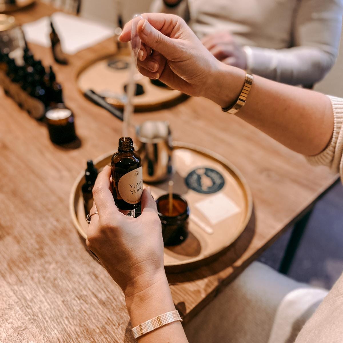 Hand füllt ätherische Dufttröpfchen in Flasche – vegane Kerzen Workshop, ideal für Team-Events.