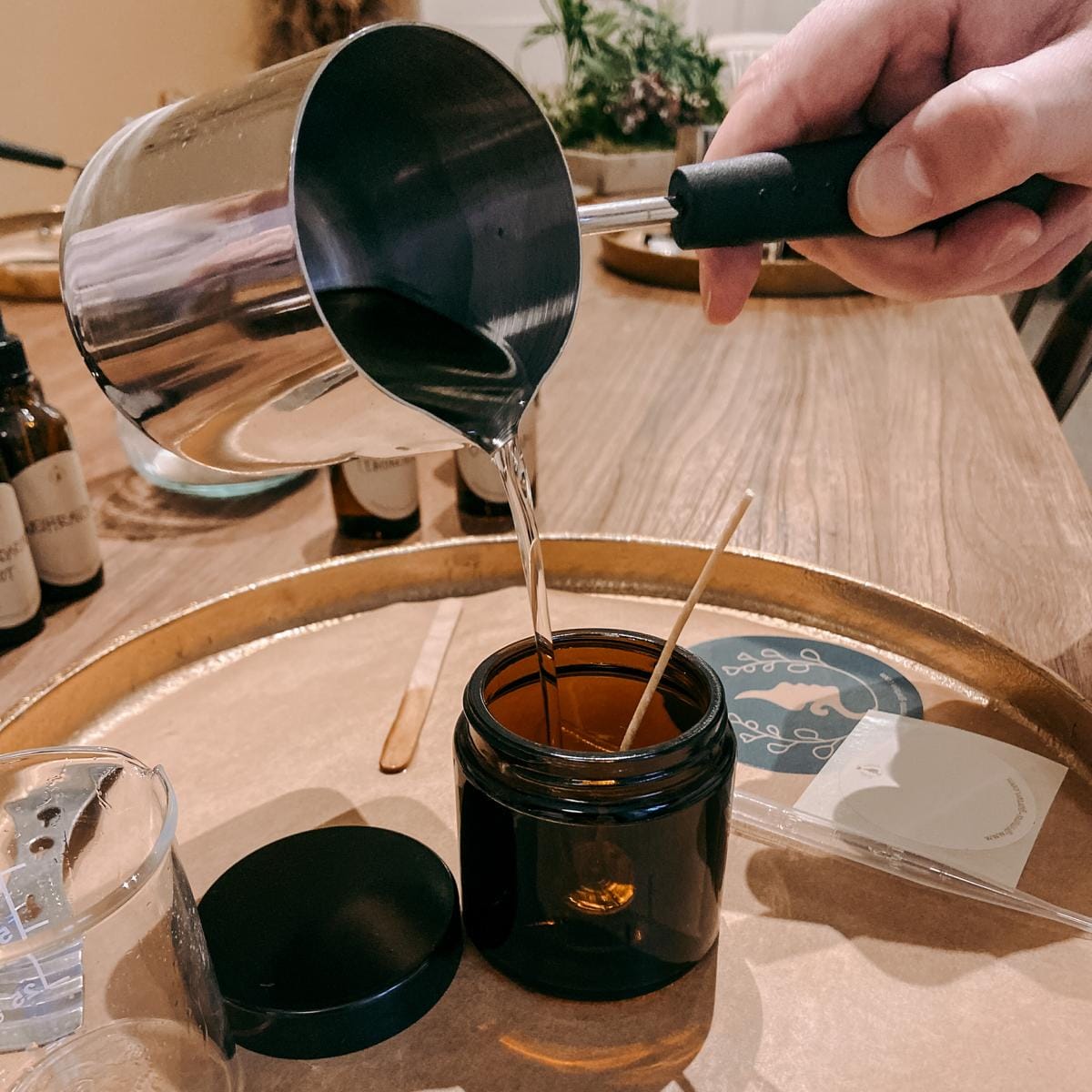 Hand füllt veganes Kerzenglas mit geschmolzenem Wachs – Duftkerzen Workshop, auch für Firmenevents.