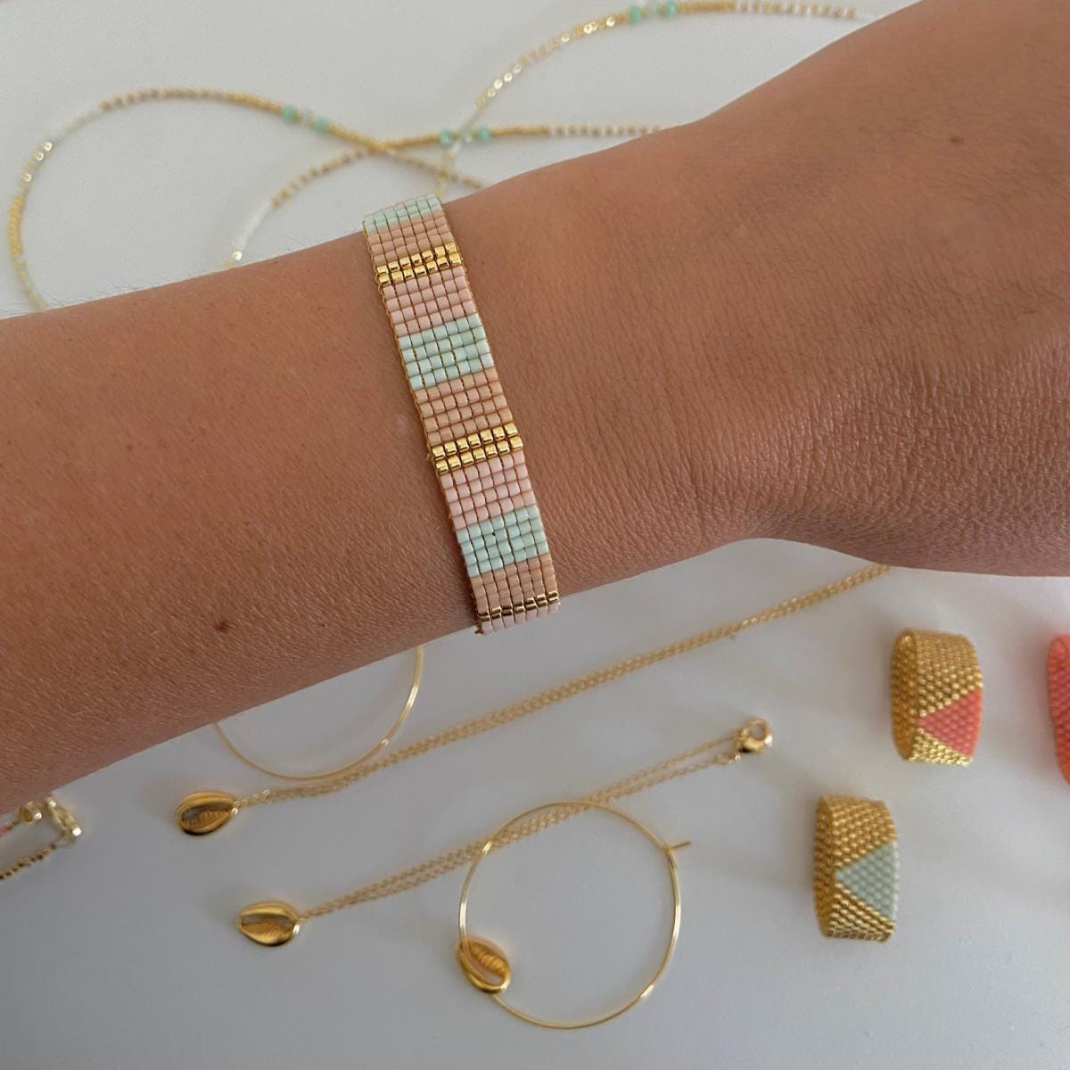 Perlenschmuck Summer Edition Armband aus blauen, rosa und goldenen Miyuki-Perlen, handgefertigt, elegantes Boho-Accessoire am Arm.