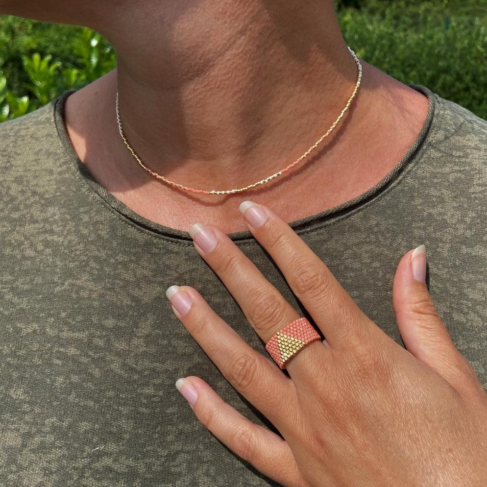 Nahaufnahme des Perlenrings aus goldfarbenen Miyuki-Perlen am Finger getragen.