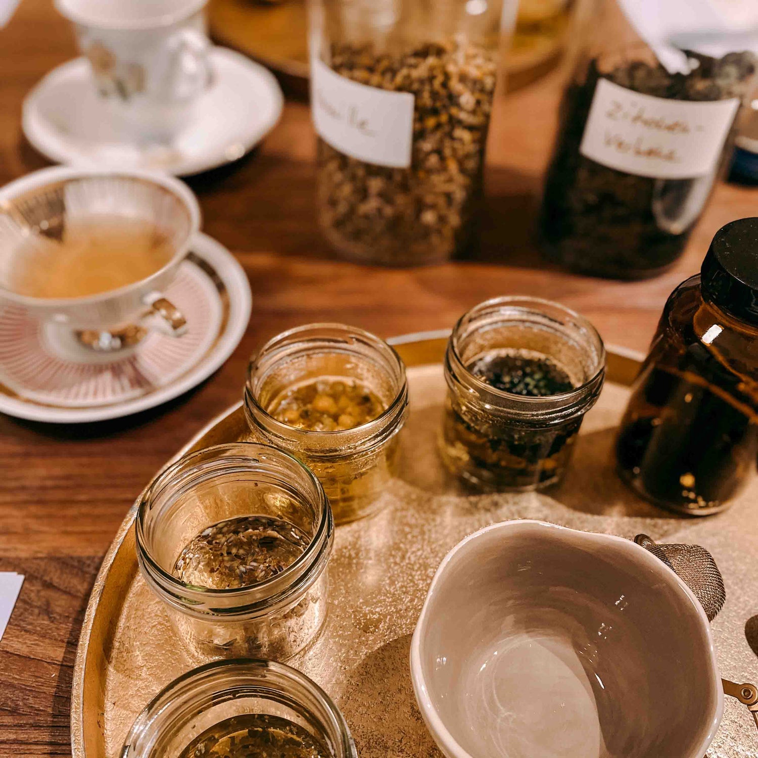 Gläser mit Kräutern und Ölen auf goldenem Tablett – kräutertee workshop, DIY Tee, Teamevent.
