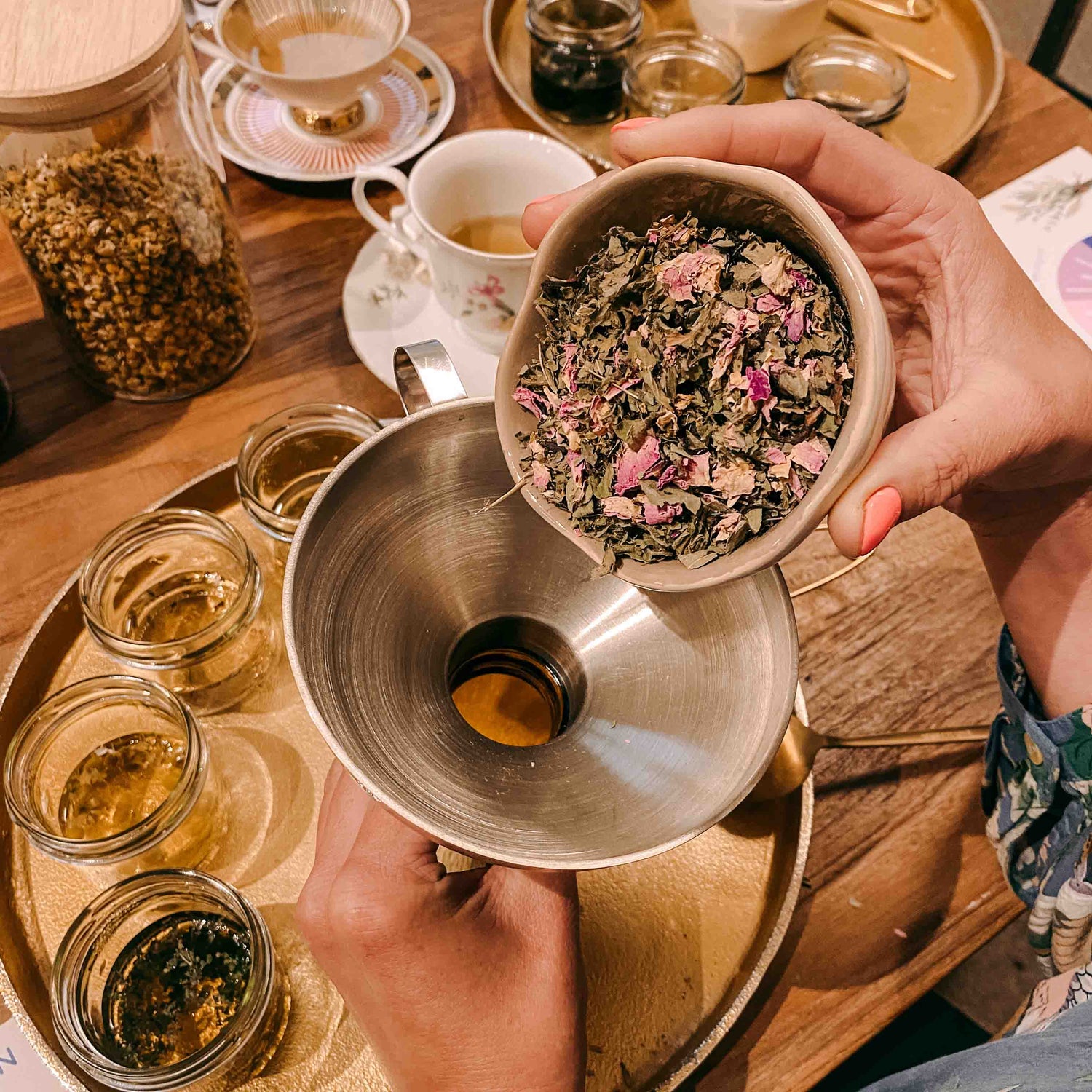 Kräutermischung wird durch Trichter in Glas geschüttet – kräutertee workshop, DIY Tee, Teamevent.