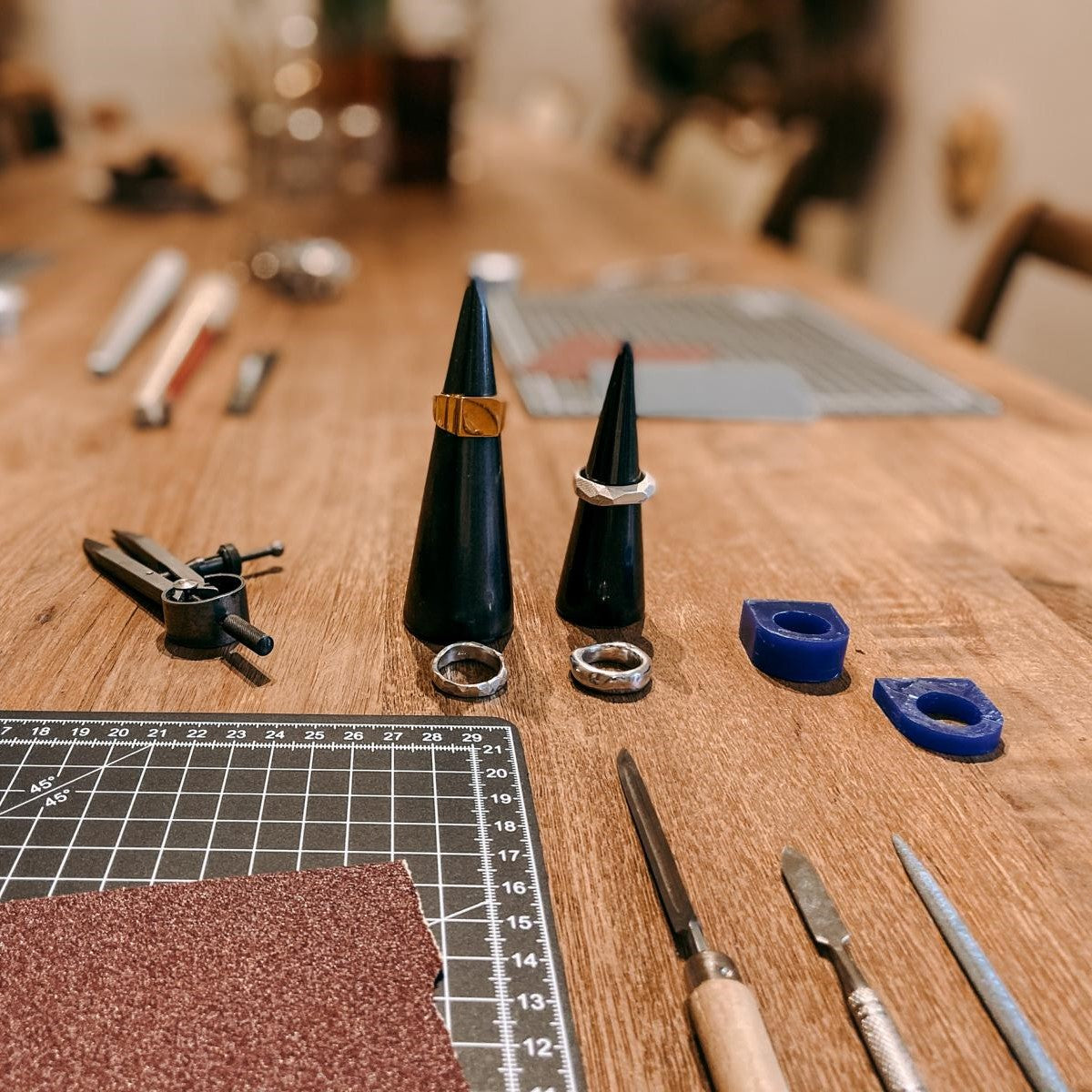 Fertige Ringe mit Materialien auf Holztisch – DIY Ring Workshop, individuelles Design, Gold- und Silberschmuck.