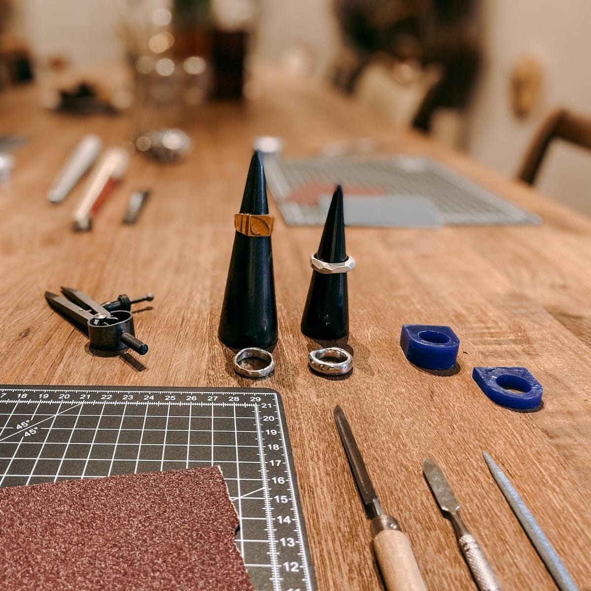 Fertige Ringe mit Materialien auf Holztisch – DIY Ring Workshop, individuelles Design, Gold- und Silberschmuck.
