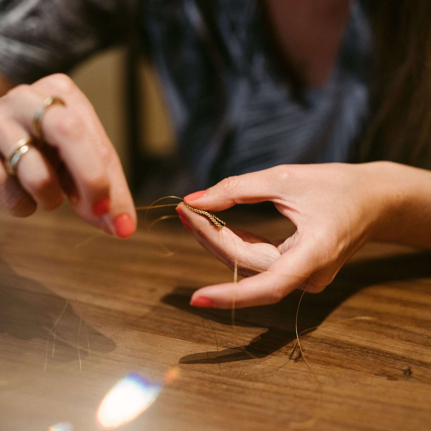 Zwei Hände fädeln goldene Perlen auf Draht – DIY Perlenring, japanische Glasperlen