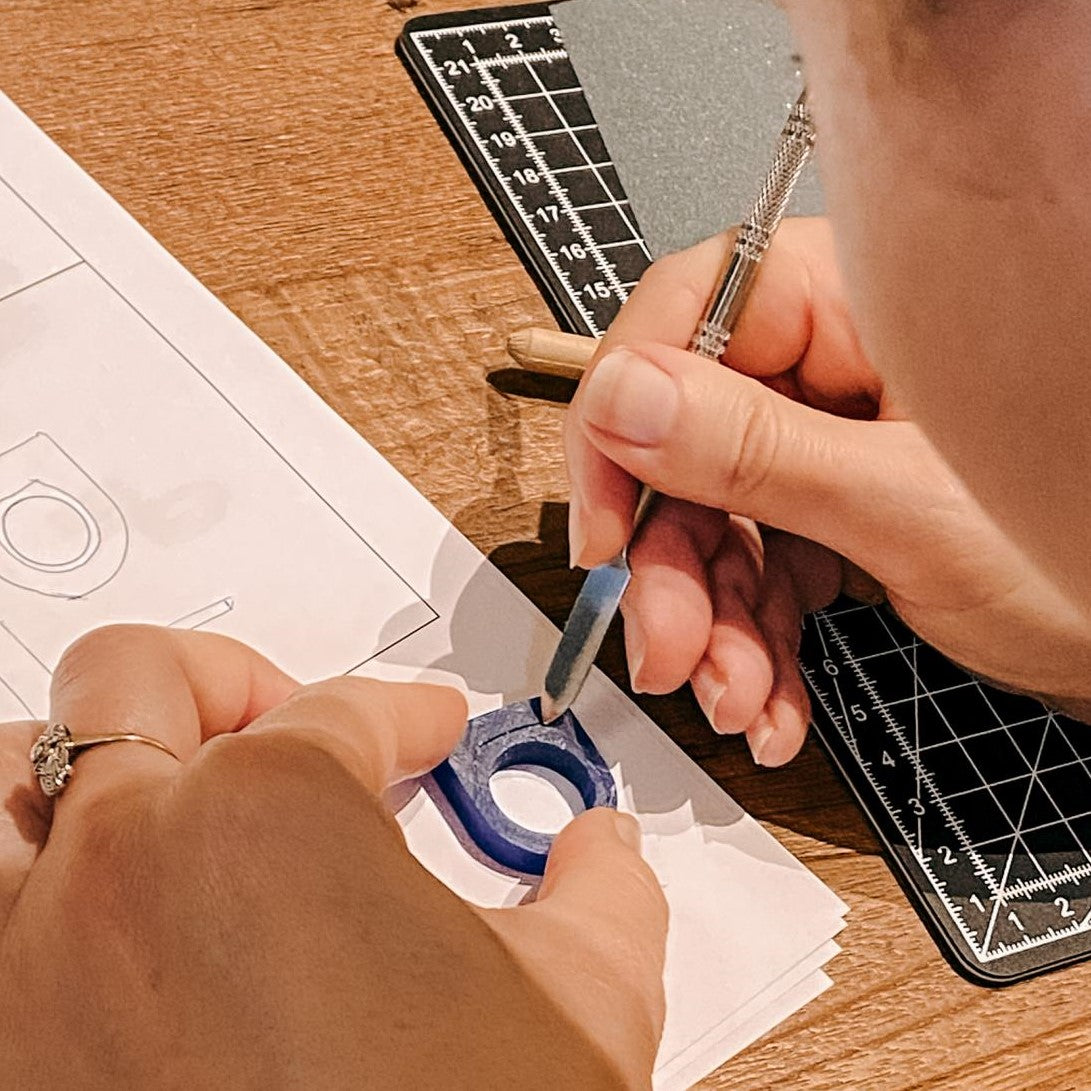 Zwei Hände bearbeiten Ringform mit Ausstechwerkzeug – DIY Schmuck, Ring selbst gestalten, Handarbeit.