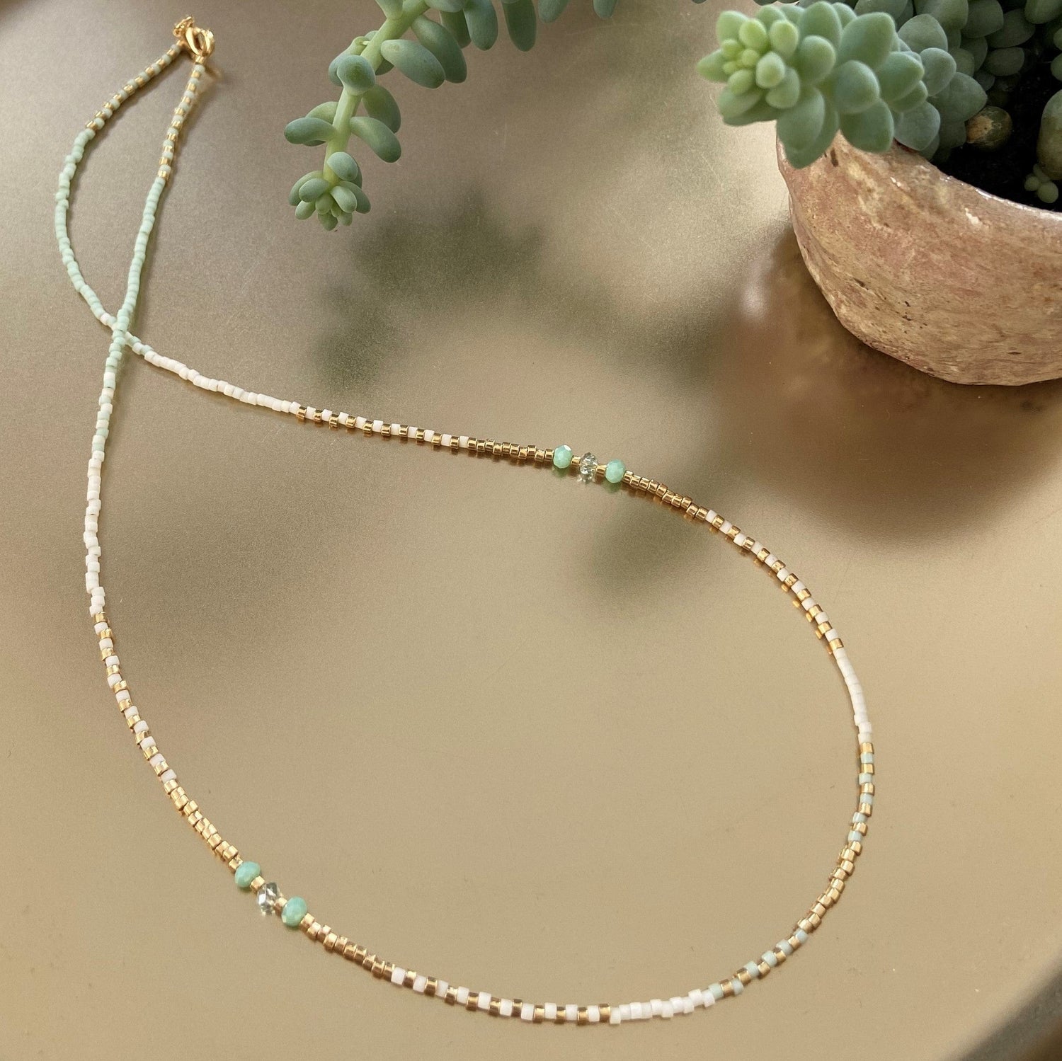 Perlenkette „Summerfeeling“ in Mint, Weiß und Gold auf Tisch liegend für sommerliches Outfit.