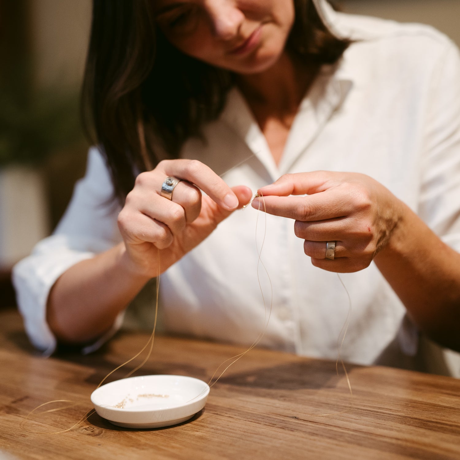 Frau fädelt Perlen von Schale auf Draht – Perlen Workshop, individueller Fingerring