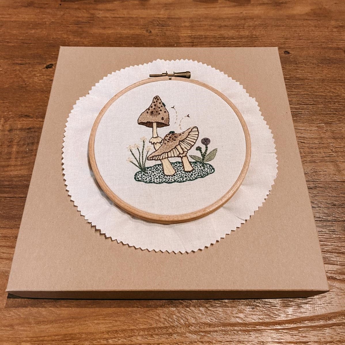 Fertiges Pilz-Stickmotiv in Holzrahmen auf Tisch – DIY Stickworkshop Pilzmotiv.
