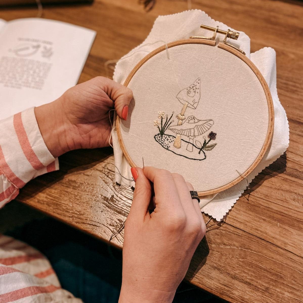 Pilzform wird von zwei Händen in Stoff eingestickt – DIY Stickworkshop.