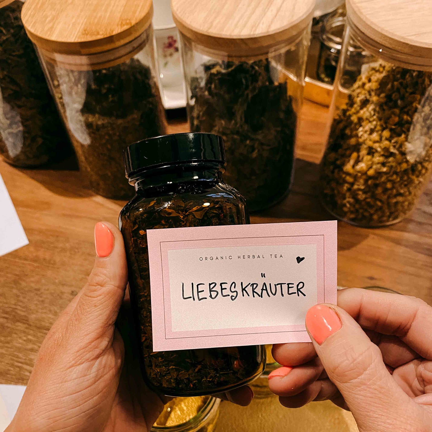 Hände halten geschlossenes Glas „Liebeskräuter“ – kräutertee workshop, DIY Tee, Teamevent.